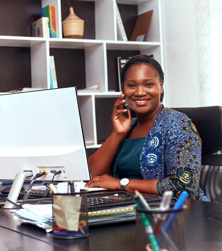 Woman Sitting In Front Of A Computer While Talking On The Phone